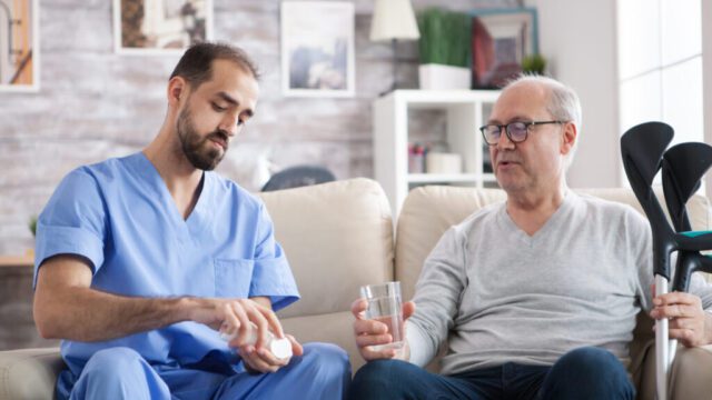 Caucasian young doctor in nursing home giving pills